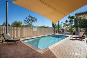 艾利斯斯普林斯Quest Alice Springs的一个带两把椅子的游泳池以及一把大伞