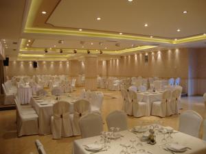 伊古迈尼察赛尔拉夫卡斯宫殿酒店的宴会厅配有白色的桌子和白色的椅子