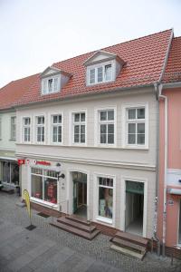 格赖夫斯瓦尔德Appartements am Markt的一座白色的大建筑,有红色的屋顶