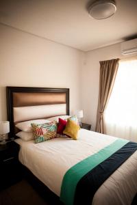 哈博罗内Apartments @ 125的一间卧室配有一张带色彩缤纷枕头的大床