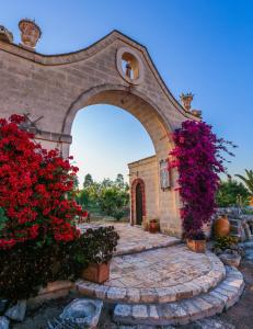 法萨诺蒙坦亚珀利昂农场酒店的花园中的一个拱门,花朵红色