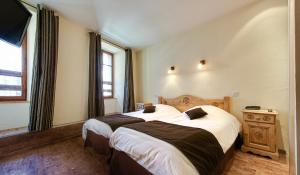 托讷Hotel Du Commerce的酒店客房设有两张床和窗户。