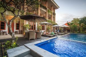 库塔旁东克安娅尔酒店的酒店设有一个游泳池,游泳池里的人坐在遮阳伞下
