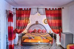 舍夫沙万达雅库摩洛哥传统庭院住宅的一间卧室配有一张带红色窗帘的大床