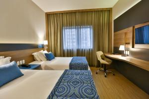 圣安德雷Hilton Garden Inn Santo Andre的酒店客房配有两张床和一张书桌