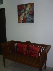 Paka北加INN酒店的一张带两个红色枕头的木沙发,挂在画底下
