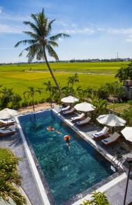 会安Hoi An Four Seasons Villa的享有带遮阳伞的游泳池的顶部景致