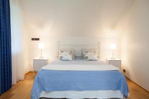 托伊拉托伊莱白色别墅公寓的一间卧室配有一张带两盏灯的蓝色床。