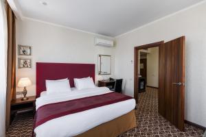 喀山雷蒙德酒店的一间卧室配有一张大床和红色床头板