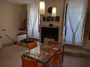 孔韦尔萨诺Lovely Stone House Conversano Puglia的客厅配有玻璃桌和橙色椅子