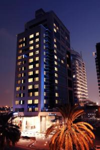 迪拜迪尔拉萨玛雅酒店的一座高大的建筑,前面有棕榈树