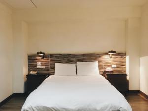 新竹华泰经典旅店的卧室配有一张带两个枕头的大白色床