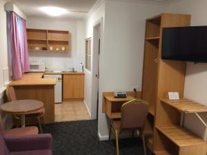 悉尼艾格克利夫汽车旅馆的客房设有带书桌和桌子的厨房。