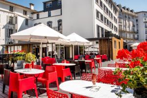 卢尔德圣罗斯酒店的一间设有红色椅子、桌子和遮阳伞的餐厅