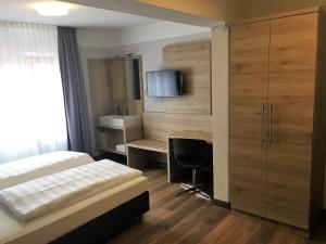 慕尼黑Eberl Hotel Pension München Feldmoching的一间卧室配有一张床、一张书桌和一台电视。