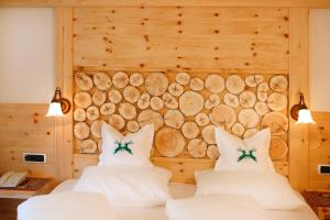 塞尔瓦迪加尔代纳山谷埃达酒店的一张木墙的房间里设有两张床