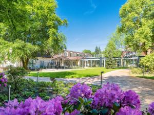 汉诺威阿姆曼兰德豪斯酒店的一座花园,在一座建筑前种有紫色花卉