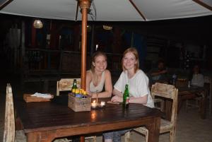 金巴兰三台巴厘岛旅馆的两个女孩坐在桌子上,拿着啤酒瓶