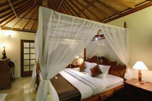 乌鲁瓦图森云别墅的一间卧室配有带蚊帐的天蓬床。