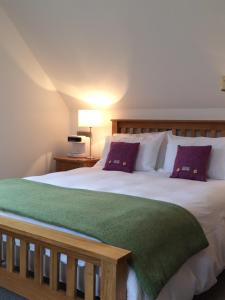 BunaveneadarLochedge Lodge的卧室配有一张带紫色枕头的大型白色床。