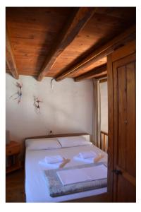 普拉卡米洛斯米洛斯瓦斯风车度假屋的一间卧室配有白色床单和木制天花板。