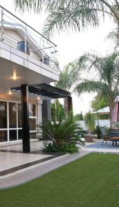 哈博罗内Cycad Palm Guest House Gaborone的带阳台和草坪的度假屋