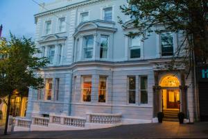 伦敦德里施奎精品酒店的一条街道上带门廊的大型白色建筑