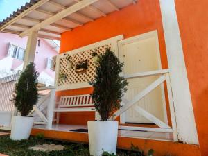 格拉玛多Glamour Gramado Residence的一座橘子房子前面有两棵盆栽的树