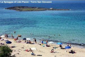 托雷圣乔万尼乌Salento Cecilia - solo settimane intere da sabato a sabato的一群人在海滩上,带遮阳伞