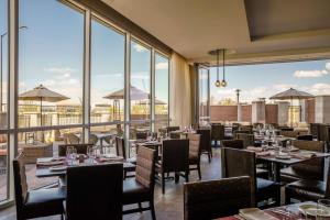 奥罗拉Hyatt Regency Aurora-Denver Conference Center的餐厅设有桌椅和大窗户。