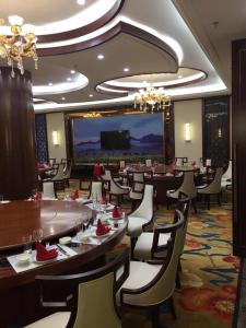 阿拉善左旗阿拉善盟左旗巴丹吉林大酒店的一间带桌椅和大屏幕的餐厅