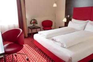 韦尔斯Best Western Plaza Hotel Wels的酒店客房,设有两张床和一张红色椅子