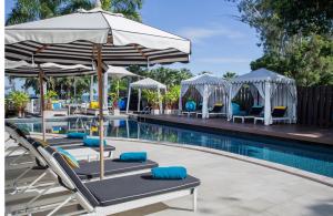 芭堤雅市中心Wave Hotel Pattaya的游泳池旁的游泳池配有躺椅和遮阳伞