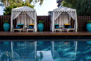 芭堤雅市中心Wave Hotel Pattaya的两个凉亭,泳池旁配有椅子