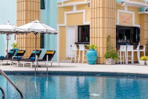 芭堤雅市中心Wave Hotel Pattaya的一座带椅子和遮阳伞的游泳池位于一座建筑旁边