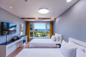 济州市Hotel Sweet Castle Jeju Hamdeok的一间卧室设有一张床和一个大窗户