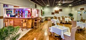 拉奇拉奇塔诺阿帕拉齐拉齐酒店的一间设有白色桌椅的餐厅和一间酒吧