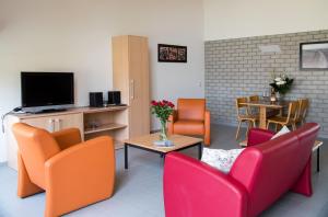 柯德科克Vakantiepark Broedershoek的客厅配有橙色和红色的椅子和桌子
