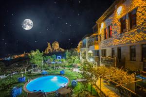 乌奇希萨尔卡利克艾维宾馆 - 特殊类别的享有夜间泳池和月亮的景色