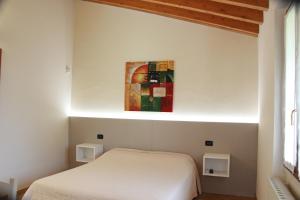 普罗瓦廖迪塞奥Villa Pasini的卧室配有白色的床和墙上的绘画作品