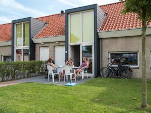 柯德科克Vakantiepark Broedershoek的一群人坐在房子外的桌子上