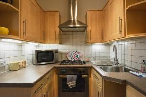 爱丁堡康慕莉班克公寓的厨房配有木制橱柜、水槽和微波炉