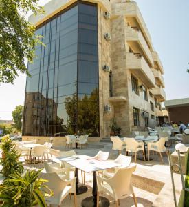 曼加利亚MSR Port Hotel的建筑前设有带桌椅的户外庭院。