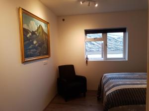 Bólstaðarhlíð波尔斯塔奥尔里奥旅馆的卧室配有绘画和床边的椅子