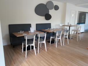 绍莱高迪尼尔酒店的用餐室配有木桌和白色椅子