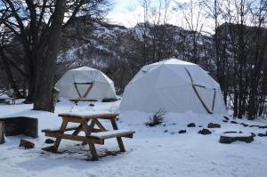 厄尔查尔坦Camping Rio de las Vueltas的雪地里的一张野餐桌和两个帐篷