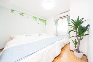 淡路NC03淡路中央公寓的卧室配有白色的床和盆栽植物