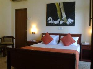 科伦坡Silvikris Villa的一间卧室配有带橙色和白色枕头的床