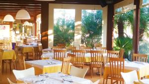 努马纳Villaggio Centro Vacanze De Angelis的餐厅设有白色的桌椅和窗户。