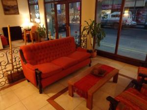 马德普拉塔科姆波斯特拉酒店的客厅配有红色的沙发和桌子